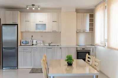 a kitchen with a table with chairs and a refrigerator at Апартамент АВА in Sandanski