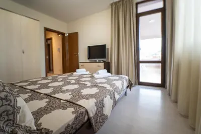 a bedroom with a bed and a tv and a window at Апартамент АВА in Sandanski