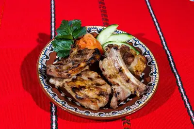 a plate of food with meat and vegetables on a red table at Hotel Melnik Хотел Мелник in Melnik