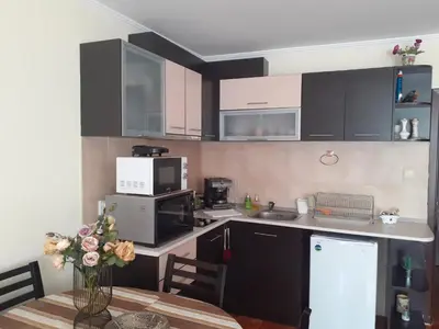 a kitchen with black cabinets and a table with a vase of flowers at Elza Apartment in Pamporovo