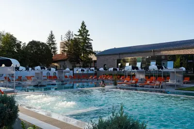 a large swimming pool with chairs and a building at Kamengrad Hotel & SPA in Panagyurishte