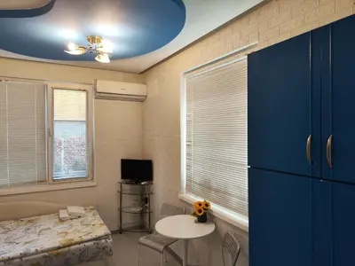 a bedroom with blue cabinets and a bed and a table at Стаи за гости Ве-Бо-Ли** in Bankya