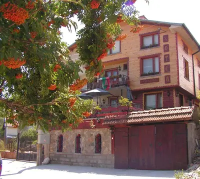 a large brick house with a red garage at Семеен хотел Калина Family hotel Kalina Говедарци in Govedartsi