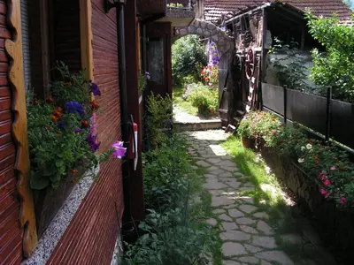 an alley with flowers on the side of a house at Семеен хотел Калина Family hotel Kalina Говедарци in Govedartsi