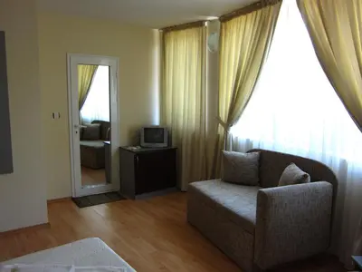 a living room with a couch and a mirror at Family Hotel Bistritsa in Sandanski