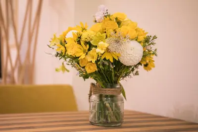 a glass jar filled with yellow flowers on a table at Este Apart - Top center in Sofia