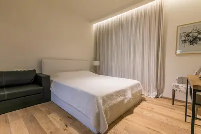a bedroom with a bed and a chair and a window at Este Apart - Top center in Sofia