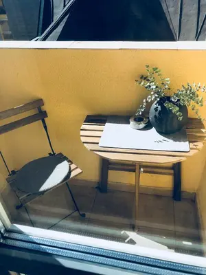 a table with a chair and a vase of flowers on it at Hip, Cosmopolitan Gem in the Heart of Sofia by Flat Mаnager in Sofia