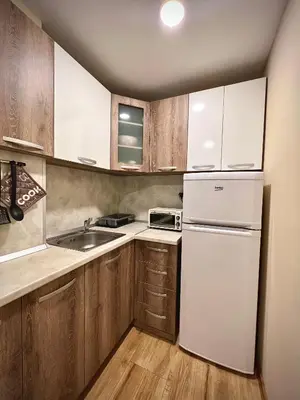 a kitchen with a white refrigerator and wooden cabinets at RELAX aпартаменти, Смолянски езера, вила ВЕНЕРА, к-с Маунтин Лейк in Smolyan