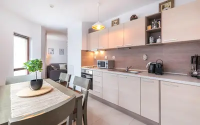 a kitchen with white cabinets and a table and a dining room at ★ Chic & Elegant 1 Bedroom in Eagle's Nest Complex ★ Close to Gondola and Bar Street in Bansko