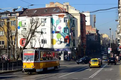 a yellow trolley car driving down a city street at Sunny studio on ulica Lyuben Karavelov in Sofia
