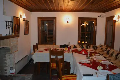 a dining room with two tables and a fireplace at Къща за гости Гайтана in Shiroka Lŭka