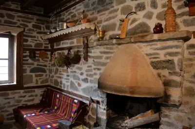 a living room with a stone fireplace with a lamp at Къща за гости Гайтана in Shiroka Lŭka