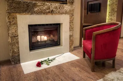 a living room with a fireplace and a red chair at Family Hotel Strannopriemnitza in Oreshak