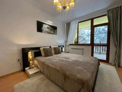 a bedroom with a large bed and a chandelier at Borovets Mountain Apartment Sequoia in Borovets