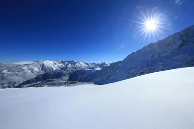 a snow covered mountain with the sun in the sky at Great location near lift in Bansko