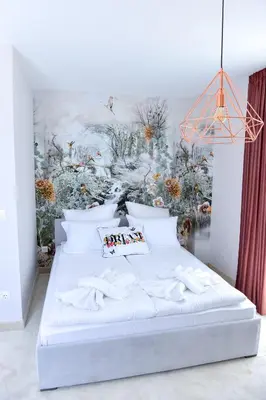 a bedroom with a white bed with a painting on the wall at Boutique Apartments Blagoevgrad in Blagoevgrad