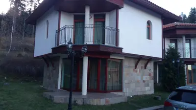a white house with red doors and a balcony at Villa Bojinovi - Forest Nook 2 in Pamporovo