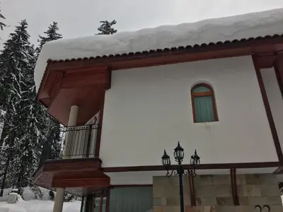 a house with snow on the roof and a window at Villa Bojinovi - Forest Nook 2 in Pamporovo