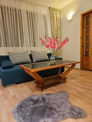 a living room with a couch and a table with flowers at Guest House Karov - 2 Stars in Chepelare