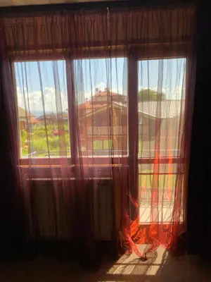 a window with curtains and a view of a house at Iglika Bansko in Bansko