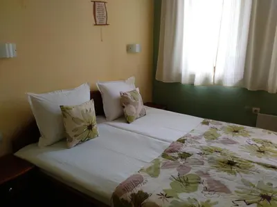 a bedroom with a bed with pillows and a window at Family Hotel Bashtina Kashta in Koprivshtitsa