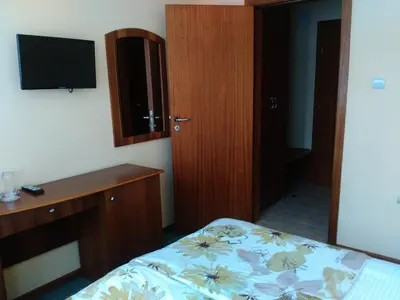 a bedroom with a bed and a desk and a television at Family Hotel Bashtina Kashta in Koprivshtitsa