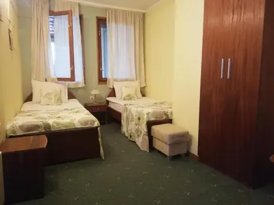 a hotel room with two beds and a cabinet at Family Hotel Bashtina Kashta in Koprivshtitsa