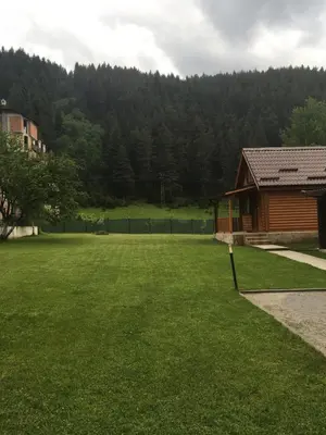 a large grassy yard with a building and a house at Еднофамилна дървена къщичка in Beli Iskar