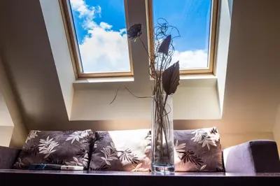 a vase with flowers sitting on a couch under a window at City Blagoevgrad Family Hotel in Blagoevgrad