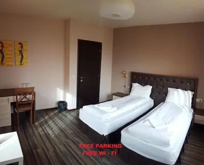 a hotel room with two beds and a desk at City Blagoevgrad Family Hotel in Blagoevgrad