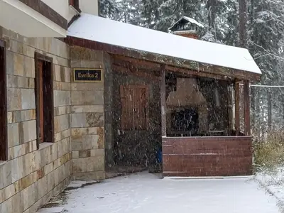 a building covered in snow with a door at Evrika Forest in Pamporovo