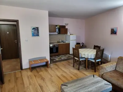 a living room with a table and a kitchen at Evrika Forest in Pamporovo