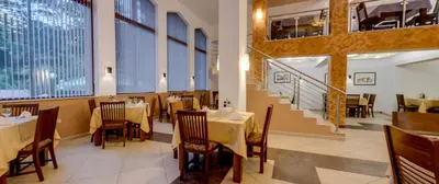 a restaurant with tables and chairs and a staircase at Balkan Hotel in Chiflik