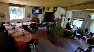 a dining room with tables and chairs and a television at Strandzhata's House in Pasarel