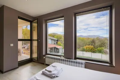 a bedroom with three windows and a bed with a view at Family Hotel Zornitsa in Ribarica