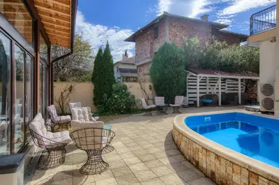 a patio with a swimming pool and chairs next to a house at Family Hotel Zornitsa in Ribarica