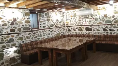 a dining room with a table and a leather couch at Боримечковата къща in Kalofer