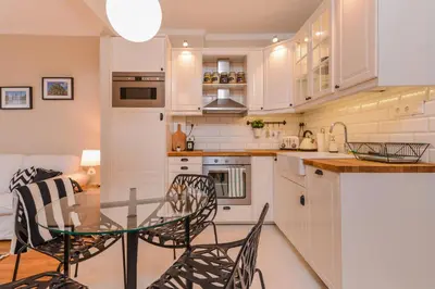 a kitchen with white cabinets and a glass table and chairs at cО́coEllie - Aesthetic 2BD Apt Near National Palace by Flat Mаnager in Sofia