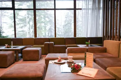 a large room with couches and tables and windows at Hotel Borovets Edelweiss in Borovets