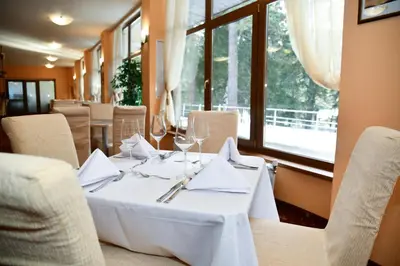 a dining room with a white table and chairs at Hotel Borovets Edelweiss in Borovets