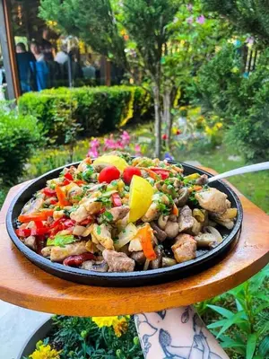 a person holding a plate of food on a table at Family Hotel Enica in Teteven