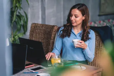 a woman sitting at a table using a laptop computer at Plaza Hotel Plovdiv - Free Parking in Plovdiv