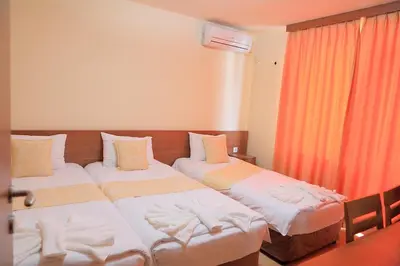 two beds in a room with orange curtains at Къща за гости 