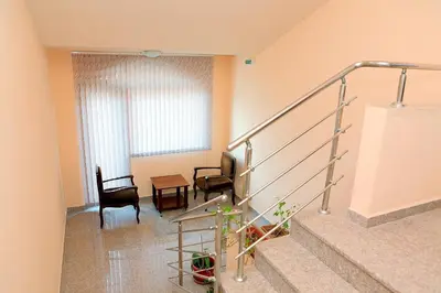 a living room with stairs and chairs and a window at Къща за гости 