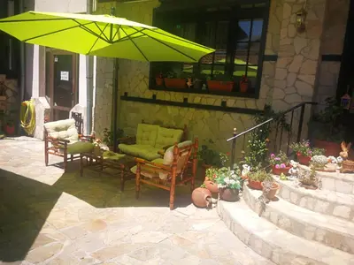 a patio with a green umbrella and chairs and plants at Hotel St. George Pobedonosets in Bansko