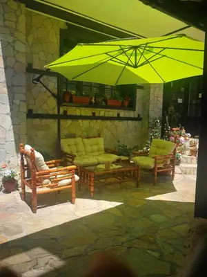 a patio with two chairs and a large yellow umbrella at Hotel St. George Pobedonosets in Bansko