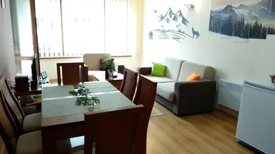 a dining room with a table and chairs and a couch at Pine Tree Apartment 2 - B7 in Bansko