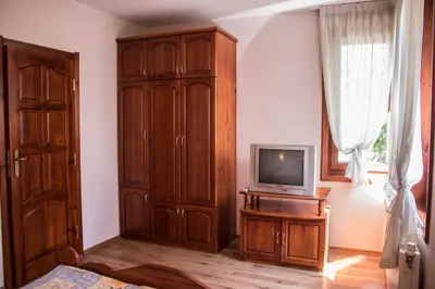 a living room with a tv and a wooden cabinet at Guest House Ilinden in Bansko