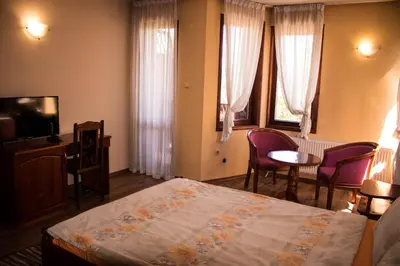 a bedroom with a bed and a table and chairs at Guest House Ilinden in Bansko